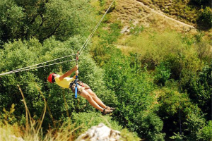 Zip line injuries: color photo of man soaring over treetops on zip line