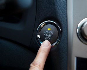 color photo of a finger pointing to a car's keyless ignition switch