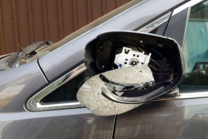 Damaged side view mirror on parked car resulting from motor vehicle accident