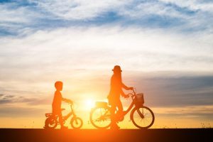 Child and parent riding bikes at sunset